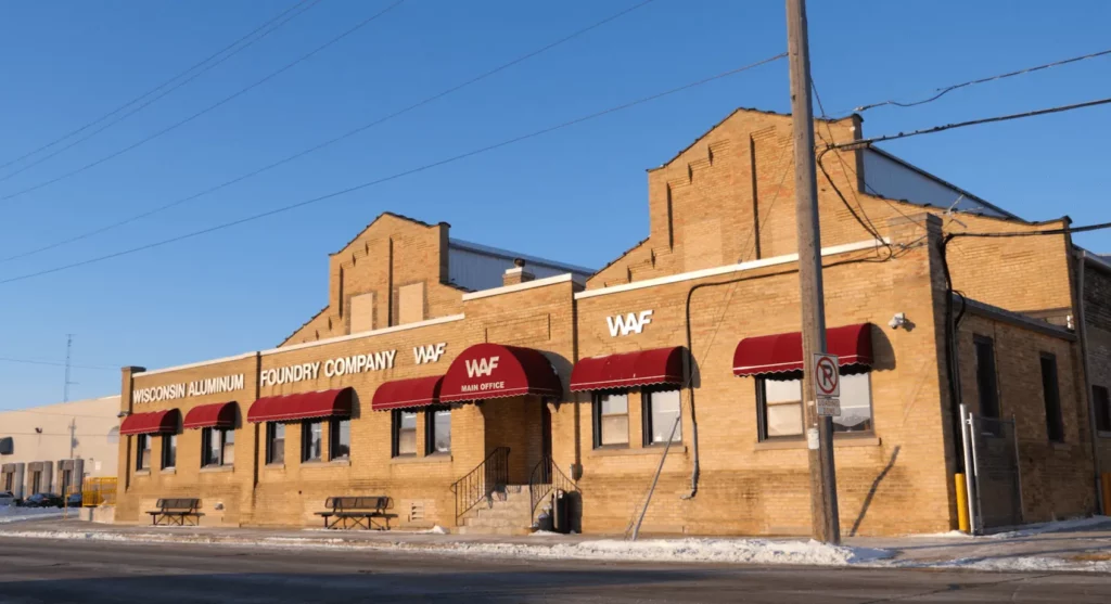 Exterior street view of Wisconsin Aluminum Foundry's main building in Manitowoc, Wisconsin, featuring brickword and red awnings.