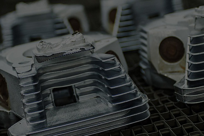 Close-up of several of the same cast aluminum parts with intricate designs on a cooling grid.