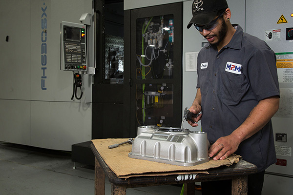 Worker at Manitowoc Pattern & Machining, a subsidiary of Wisconsin Aluminum Foundry, works on a casting set on a table.