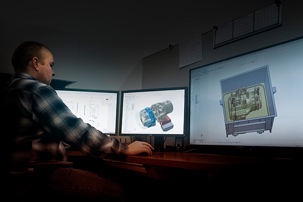 A Wisconsin Aluminum Foundry process design and engineer works at a computer with three screens on a 3D model.