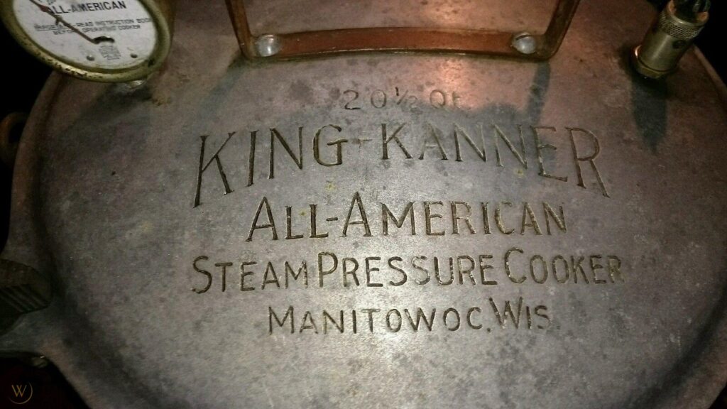 Top of a pressure cooker lid carved with the words "King Kanner All-American Steam Pressure Cooker, Manitowoc, Wis."
