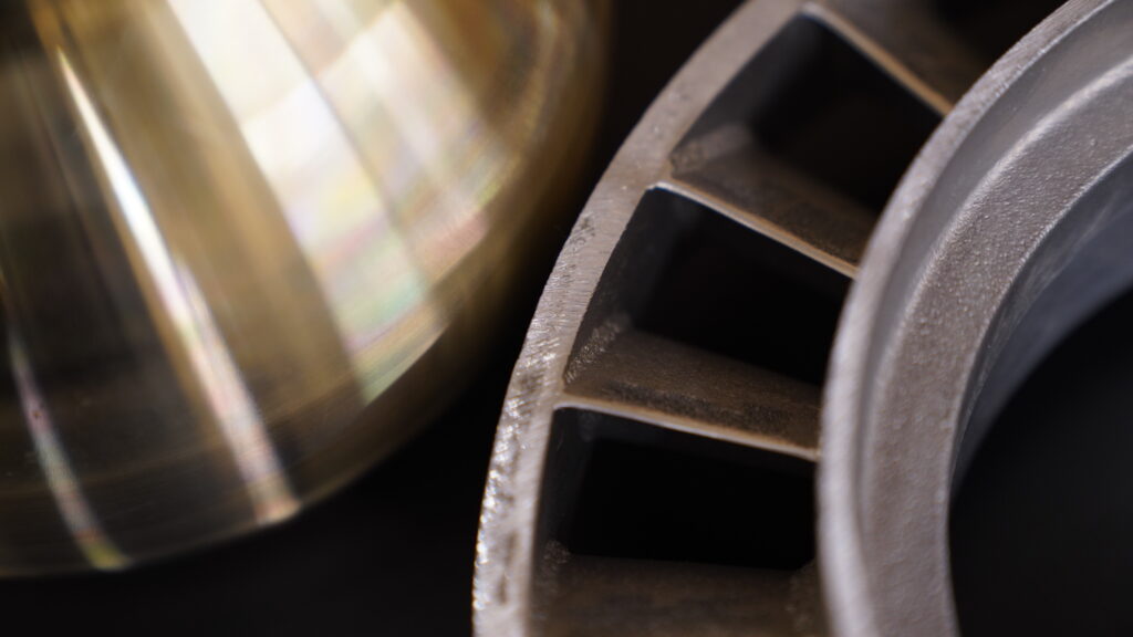 Close view of smooth-surfaced bronze and brass beside a circular aluminum casting.