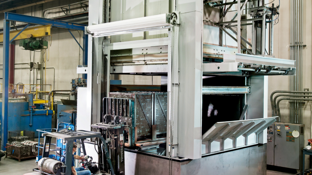 Worker at ATEK Metal Technologies, a Wisconsin Aluminum Foundry company, uses a lift to unload cast metal parts from a heat treatment furnace.