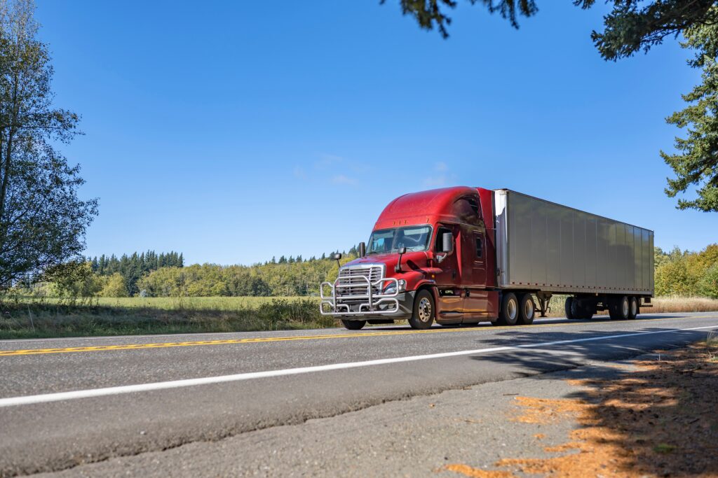 A semi truck drives down a highway at high speed.