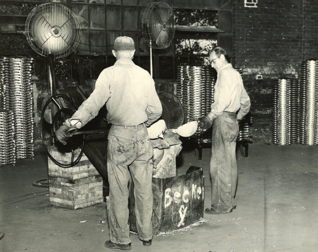 Two Wisconsin Aluminum Foundry employees operate a pour machine circa 1960s.