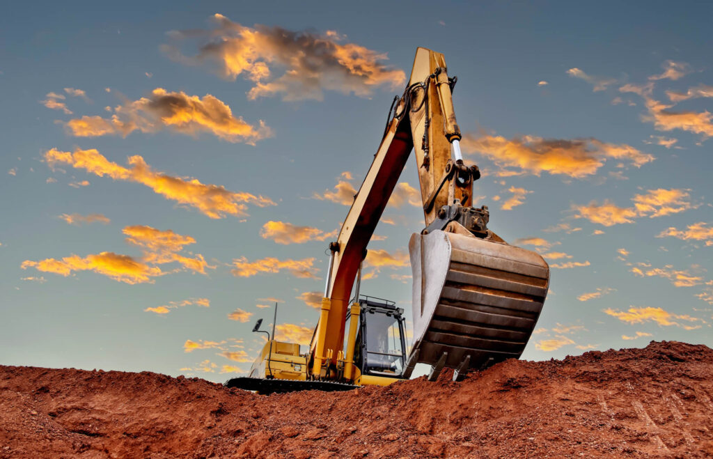 Excavator on a construction job site, bucket raised to dig.